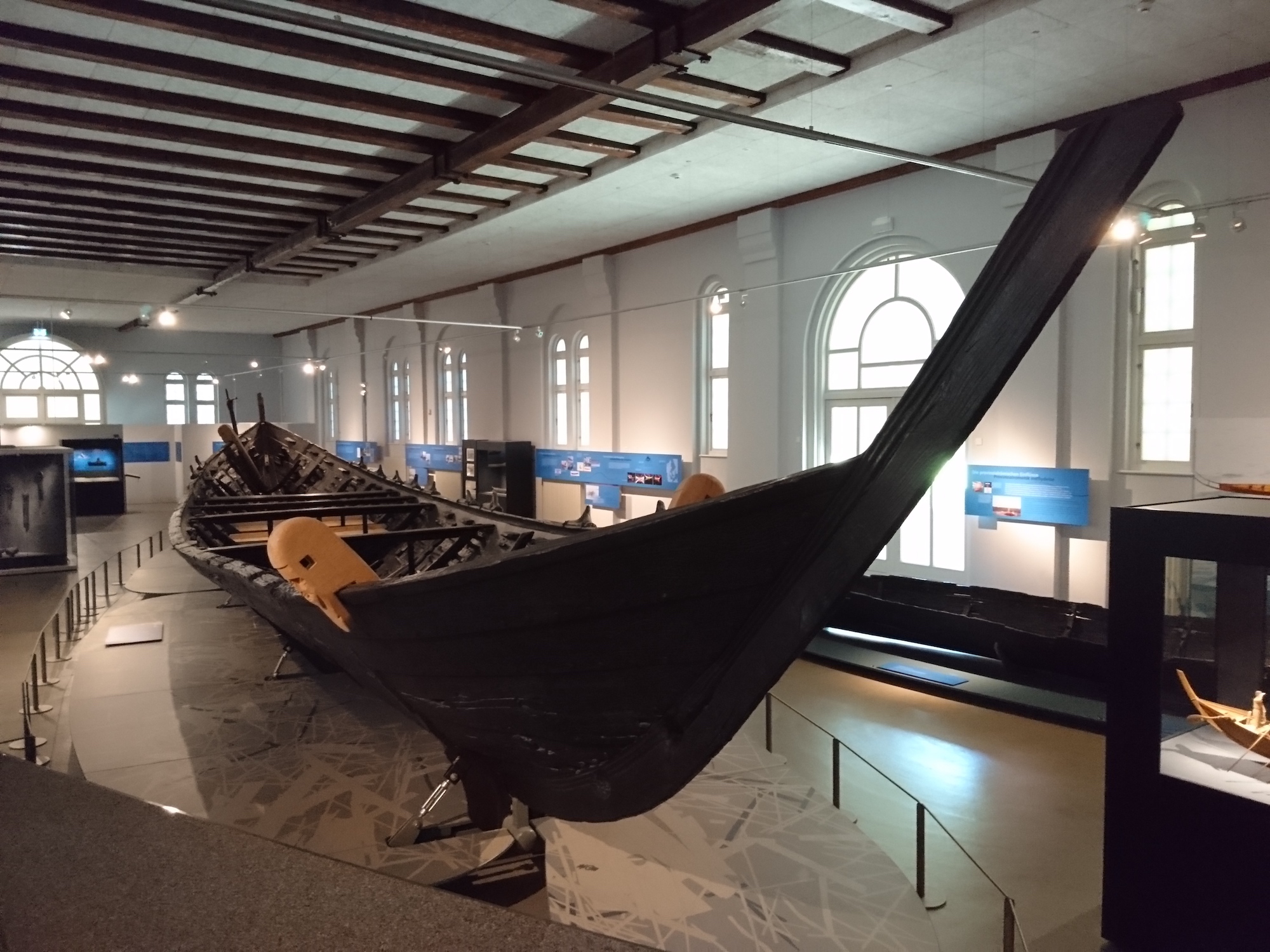 Ein altes, großes, dunkles Ruderboot in einem Museum.